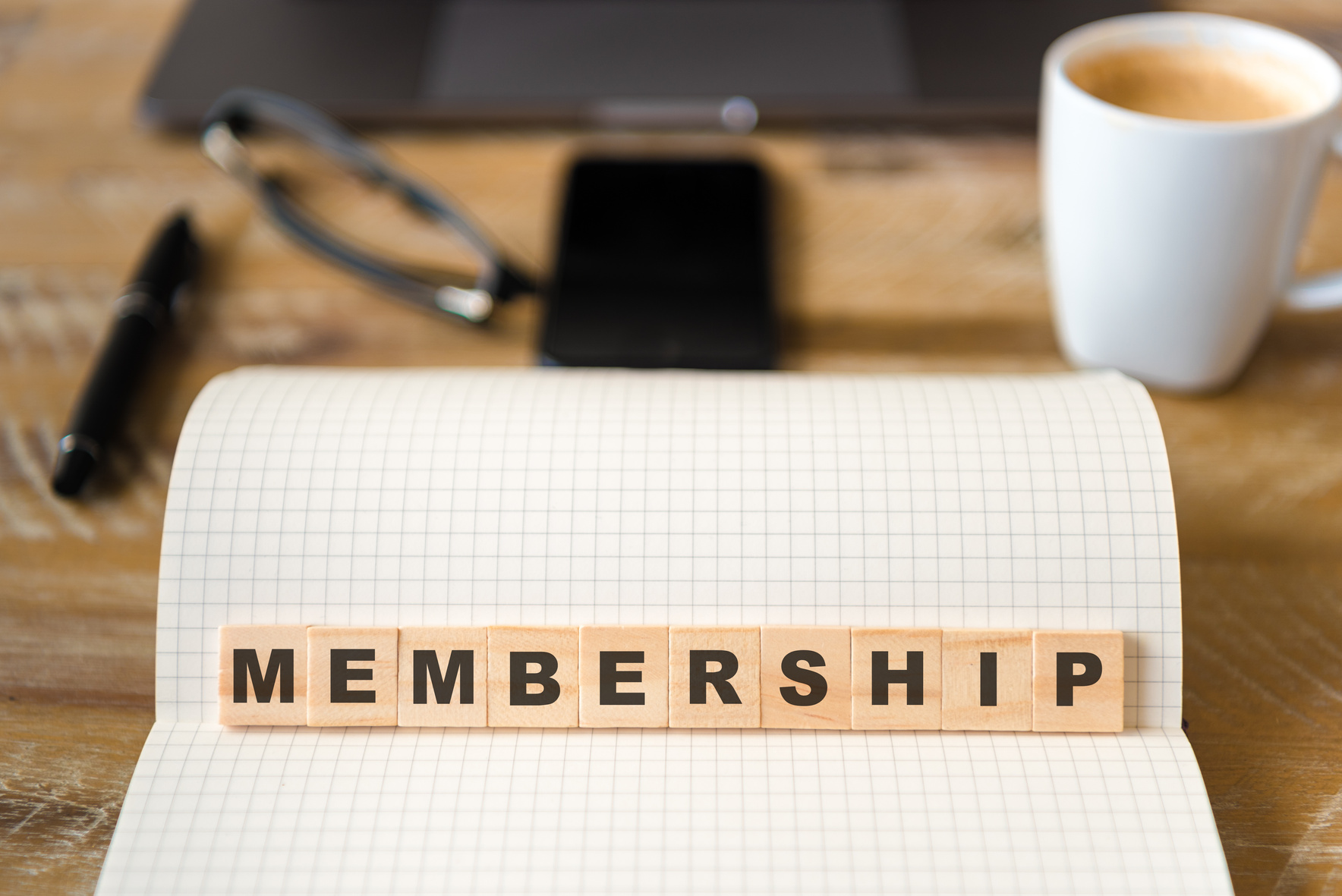 Closeup on notebook over wood table background, focus on wooden blocks with letters making Membership text
